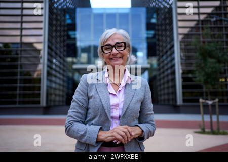 Befähigte und lächelnde reife Geschäftsfrau mit Händen am Arbeitsplatz und Blick auf die Kamera. Stockfoto