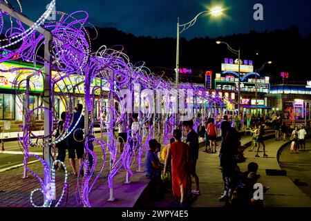 Sokcho City, Südkorea - 30. Juli 2019: Die Menschen schlendern nachts entlang der kurvenreichen Straße des Daepo Port, beleuchtet von bunten dekorativen Lichtern, mit Stockfoto