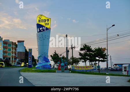 Yangyang County, Südkorea - 30. Juli 2019: Die beleuchtete Eingangsskulptur des Hujin Port, eine hohe zylindrische Struktur mit Fischmotiven, wird gekrönt Stockfoto