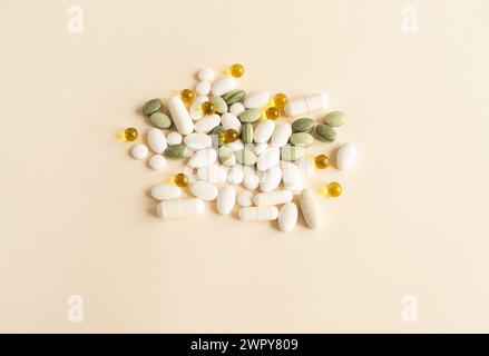 Verschiedene Stapel von bunten Pillen, Grün weiß Gelb, Beige Tabletten, Vitamine, Kapseln, medizinische Beilage auf beigem Hintergrund. Pharmazeutisches Konzept Stockfoto