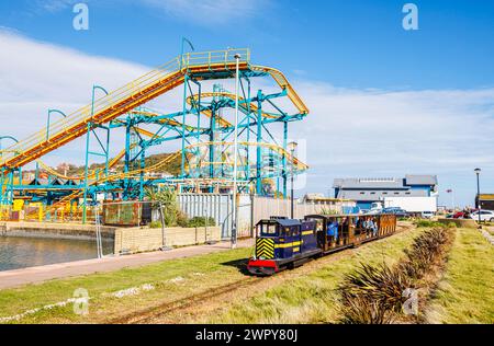 Hastings Miniatur-Eisenbahnlok „Speedy Fizzle“ vor der drehenden Pinball X-Achterbahn im Flamingo Park, Old Hastings, East Sussex, England Stockfoto