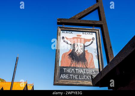Amüsantes hölzernes Schild mit Blackbeard und „Them that stirbt are the Lucky Ones“ im Stade in der Altstadt von Hastings, East Sussex, England Stockfoto
