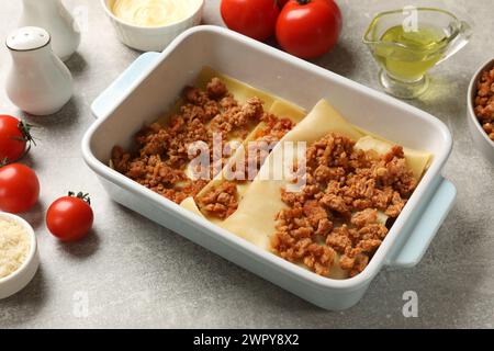 Lasagne kochen. Nudelblätter und Hackfleisch in Backblech auf einem hellen, strukturierten Tisch Stockfoto
