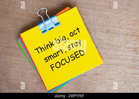 Denken Sie groß, verhalten Sie sich intelligent, bleiben Sie konzentriert Text auf gelbem Notizblock. Inspirierendes Konzept. Stockfoto