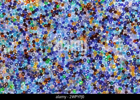 Abstrakter Hintergrund aus mehrfarbigen Glasperlen zum Sticken. Mehrfarbiges Muster mit Bodenbeleuchtung Stockfoto