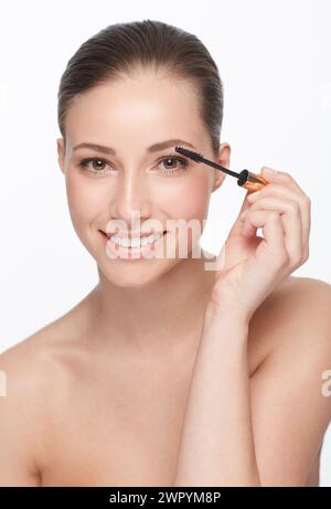 Frau, Porträt und Hautpflege für Schönheit, Mascara und Make-up mit Wimpern und Kosmetik auf weißem Hintergrund. Gesicht, Zauberstab für Wimpernverlängerung und Haut Stockfoto