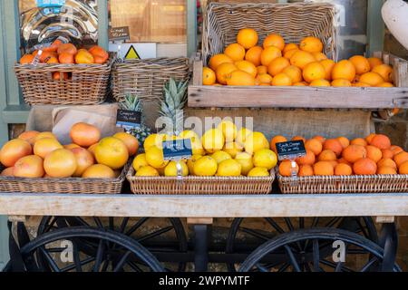 Orangen, Zitronen, Grapefruit zum Verkauf auf einem Wagen vor dem Eagles Fine Foods Shop. Deddington, Oxfordshire, England Stockfoto