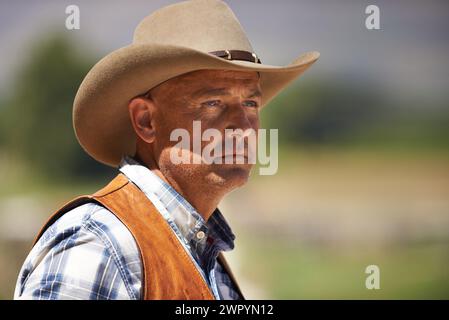 Cowboy, Ranch und Denken im Freien, Sonne und ernst für Wrangler und Texas Farmer im Stall. Reifer Mann, wilder Westen und Sommer in der Landwirtschaft, Hut Stockfoto