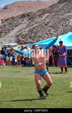 CHOVD, MONGOLEI - 6. JULI 2017: Mongolisches Nomadenlager. Mongolische Wrestler, die in der Natur kämpfen. Zuschauer in Nationalkleidung beobachten den Wettbewerb. Stockfoto