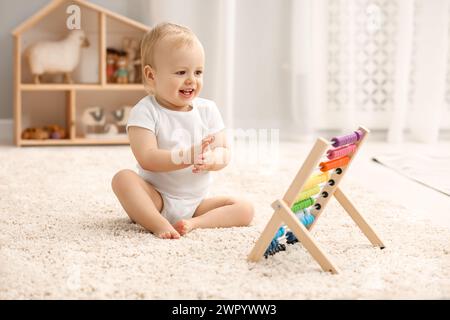 Kinderspielzeug. Süßer kleiner Junge und hölzerner Abakus auf Teppich zu Hause Stockfoto