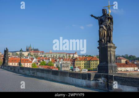Statue von St. Johannes der Täufer auf der Karlsbrücke, mit Hradcany Castle und St. Vitusdom im Hintergrund, in Prag, Tschechien, sonnig Stockfoto