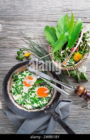 Spiegeleier in einer Pfanne mit frischen Frühlingspflanzen. Gesunde Frühlingsdiät-Ernährungskonzepte. Stockfoto