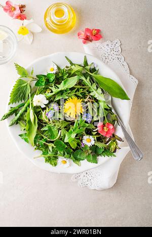 Frühlingssalat mit Blumen, Kräutern und Pflanzen. Wilder Knoblauch, Brennnessel, Löwenzahn und andere Heilkräuter sowie wilde essbare Pflanzen, die im Frühjahr wachsen. Stockfoto