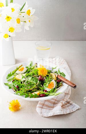 Löwenzahnsalat mit Eiern, Kartoffeln und Bohnen auf hellen Tischhintergrund Stockfoto