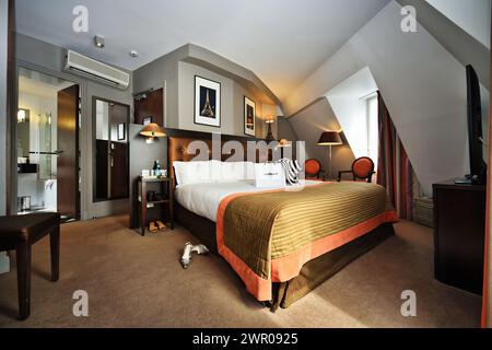 Paris, Frankreich, ein geräumiges Hotelzimmer im Dachgeschoss mit gerahmten Fotografien des Eiffelturms, Lampen, Stühle, Zeichnungen und Modegeschäften Stockfoto