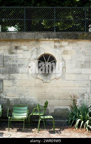 Eine Gruppe grüner Stühle an einer Steinmauer mit rundem Fenster in den Tuilerien Jardin Paris, Frankreich Stockfoto