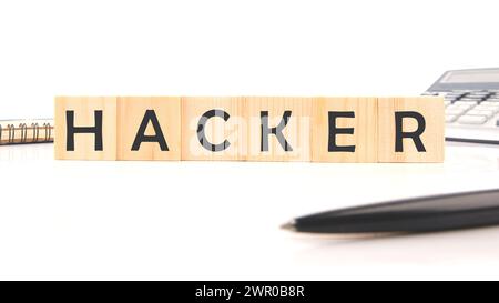 Hackerwort auf Holzwürfeln neben einem Taschenrechner, Stift, Notizblock auf weißem Hintergrund Stockfoto