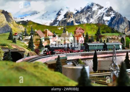 Miniaturbahnmodell mit Modelldampflokomotivzug in Bergambiente. Spielzeugzug Stockfoto