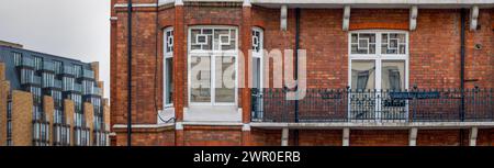 Balkon mit klassischen weißen Fenstern aus typischer Londoner Architektur mit roter Backsteinwand und Panoramafanner Stockfoto