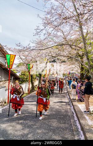 Tatsuno Samurai Parade unter Kirschblüten mit zwei Mädchen in Heian Rüstung, gefolgt von der Prozession der Samurai. Menschen beobachten. Stockfoto