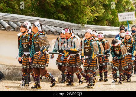 Japanische Kinder, die als Aschigaru-Soldaten gekleidet sind, marschieren bei der Samurai-Parade an einer alten Schlosswand in Tatsuno entlang. Stockfoto