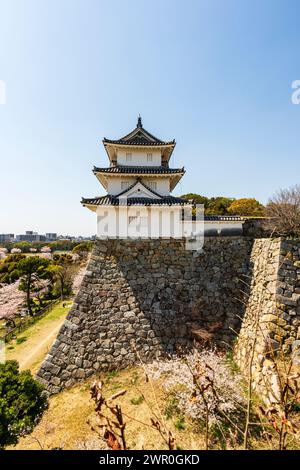 Schloss Akashi, Japan. Der tatsumi Yagura, Turm, auf hohen steilen Ishigaki Steinmauern vor einem klaren blauen Himmel in der Frühlingssonne. Stockfoto