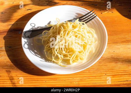Teller mit italienischer Pasta auf einem von der Sonne beleuchteten Holztisch. Nationale Gerichte Stockfoto
