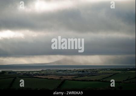 Blick über Dundrum Bay am nassen Winternachmittag; Newcastle und Mournes hinter Regenvorhang; Himmel mit grauen Wolkenbändern. Stockfoto