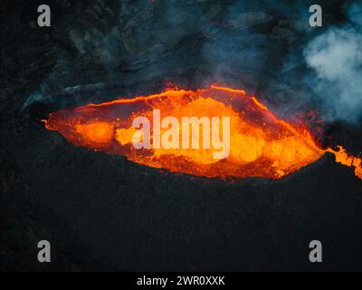 Fließende Lava, heißes Magma, das aus dem Vulkankrater fließt, Seitenansicht aus der Luft. Konzepte von Vulkanausbruch und isländischem Feuer- und Eisland. Stockfoto