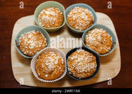Sechs Muffins in Cupcake-Kisten auf einem Holzbrett Stockfoto