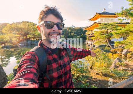 Hübscher junger Tourist, der Sommerurlaub in Kyoto, Japan, genießt - Reisender Lebensstil-Konzept mit lächelndem Mann, der mit japan Selfie auf der Stadtstraße macht Stockfoto