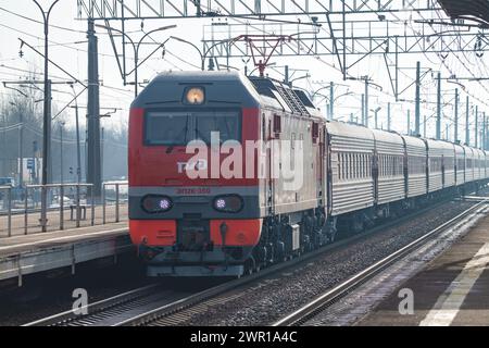 PETRO-SLAVJANKA, RUSSLAND - 4. MÄRZ 2024: Elektrolokomotive EP2K-350 mit Personenzug auf dem Bahnhof Slavjanka an einem Märztag. Oktjabrskaja Ra Stockfoto