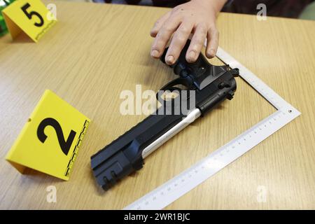 Aschersleben, Deutschland. März 2024. Eine Schusswaffe und Beweismarkierungen liegen auf einem Tisch für Trainingszwecke in einer "Tatortwohnung" der Polizeiakademie. An der Polizeiakademie in Aschersleben wurde ein neues forensisches Ausbildungszentrum für angehende Kriminologen eingerichtet. Quelle: Matthias Bein/dpa/Alamy Live News Stockfoto