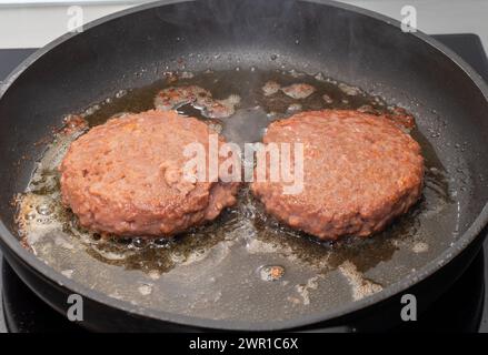 Schweiz 10.03.2024: Beyond Meat Burgers in Teflonpfanne werden frittiert. Darstellung der Zubereitung pflanzlicher Fleischersatzstoffe. Stockfoto