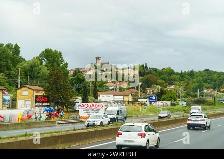 Lyon, Frankreich - 7. Mai 2023: Mehrere Autos fahren auf einer Autobahn mit einem markanten Hügel im Hintergrund. Die Fahrzeuge bewegen sich entlang der r Stockfoto