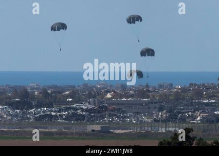 Süd-Israel, Israel. März 2024. Die C-130 der United States Air Force wirft humanitäre Hilfe per Fallschirm über dem nördlichen Gazastreifen ab, wie sie am 10. März 2024 aus dem Inneren Israels gesehen wird. Die USA und andere Länder geben weiterhin Nahrungsmittel und andere humanitäre Hilfsgüter für dringend bedürftige Palästinenser im Gazastreifen kurz vor Beginn des Heiligen Monats Ramadan ab, während Israels Krieg gegen die Hamas fortgesetzt wird. Dahinter ist das Mittelmeer zu sehen. Foto von Jim Hollander/UPI Credit: UPI/Alamy Live News Stockfoto