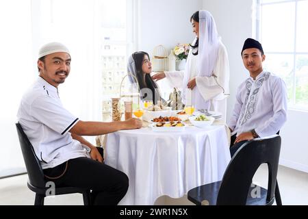 Die Freundschaft von Frauen und Männern feiert Eid al Fitr oder Hari Raya, indem sie zusammen essen und reden. Stockfoto