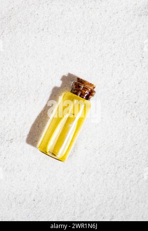 Ätherisches Öl in Glasflasche auf Sand, Draufsicht Stockfoto