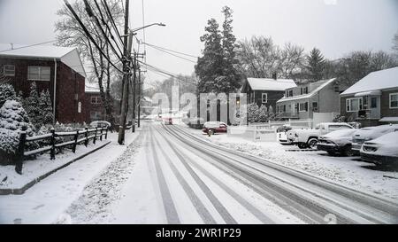 NORWALK, CT, USA - 13. FEBRUAR 2024: Wohngebiete sind in der Straße mit Schnee bedeckt und Autos in der Entfernung am Schneesturm Tag im Februar 2024 Stockfoto