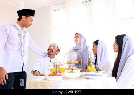 Begeisterte asiatische Familien oder Freunde feiern Hari Raya Idul Fitri Eid al Fitr, reden und essen gemeinsam Stockfoto