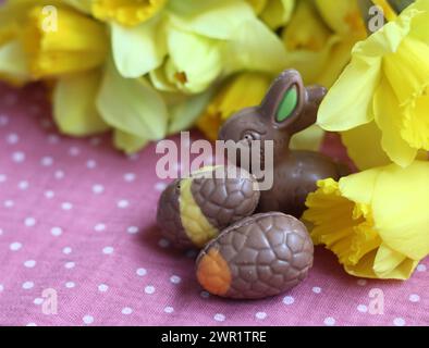 Milchschokolade-Häschen und Eier auf einem Tisch. Helle und farbenfrohe Osterkarte. Stockfoto