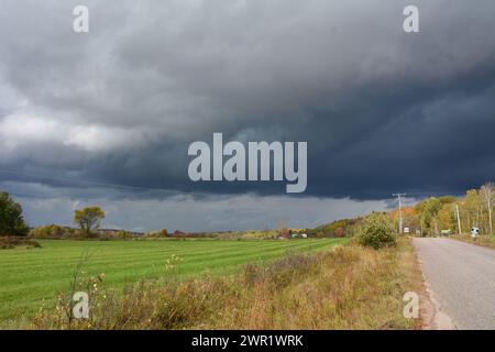 Entferntes weißes Bauernhaus, das sich in Wasser auf der Einfahrt vor dem Sturm spiegelt Stockfoto