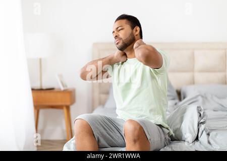 Unglücklicher Schwarzer, der nach dem Aufwachen unter Nackenschmerzen leidet Stockfoto