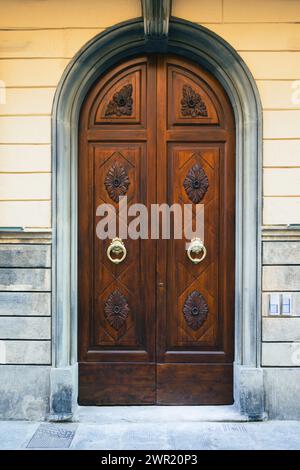 Eleganter alter Doppeltür-Eingang eines rosafarbenen Ziegelgebäudes in Europa. Alte Holztür eines alten Steinhauses. Einfache braune Holztür. Architektur Stockfoto