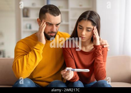 Porträt Von Verärgerten Ehegatten Mit Blick Auf Den Negativen Schwangerschaftstest, Leiden Unter Unfruchtbarkeitsproblemen Stockfoto