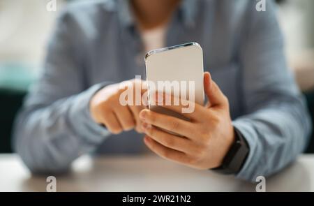 Nahaufnahme der Hände eines Mannes mit einem Smartphone, fokussieren auf den Bildschirm mit verschwommenem Hintergrund Stockfoto