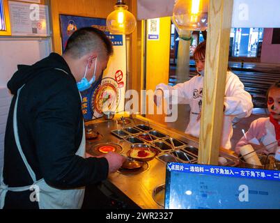 Leshan, China, Chinesische Familie, die Essen in Take Away kauft, Chinesisches Restaurant, Mann, der im Fenster arbeitet, Fast-Food-Arbeiter Stockfoto