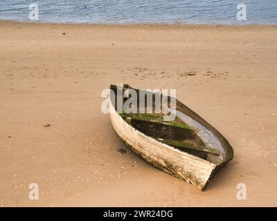 Rustikales altes Boot vor Anker am Sandstrand bei Niedrigwasser Stockfoto