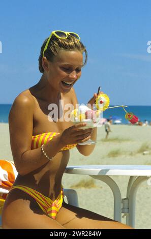 Schönheit Strand blondes Haar junge Frau isst Eis Bue Himmel Hintergrund Stockfoto
