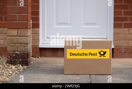 Exeter, UK-10. März 2024: Ein Versandkarton der Deutschen Post vor einer Haustür. Die Deutsche Post ist eine Marke der DHL Group, die für ihre Inlandssendungen verwendet wird Stockfoto